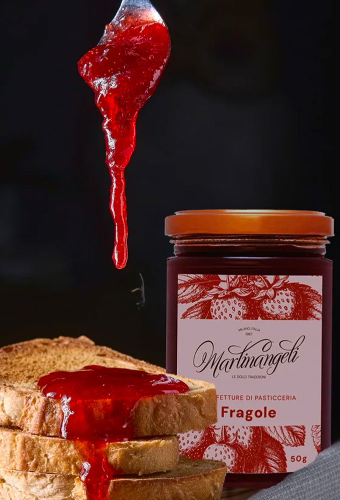 Confettura artigianale di fragole della Pasticceria Martinangeli (Le Dolci Tradizioni), presentata in un vasetto elegante e servita su fette di pane tostato per una colazione o merenda genuina.