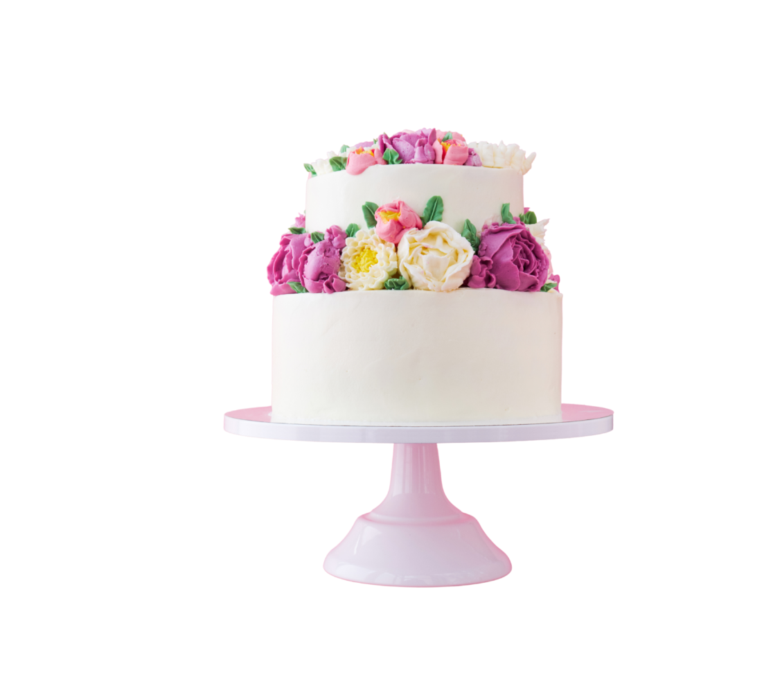 Dettaglio di una raffinata torta artigianale ricoperta di panna bianca, decorata con una fitta ghirlanda di fiori in crema nei toni del rosa, fucsia e bianco, presentata su un'alzata di colore rosa.