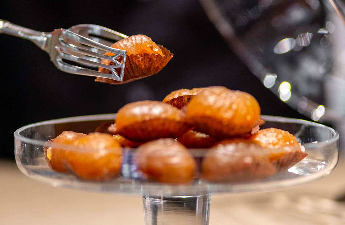 Raffinati marron glacé artigianali serviti in eleganti pirottini e presentati su un'alzata di vetro, una prelibatezza della Pasticceria Martinangeli (Le Dolci Tradizioni).